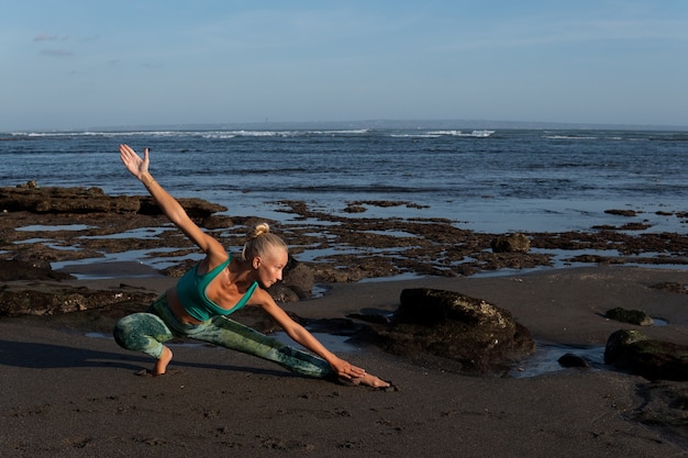 Bella donna che fa yoga sulla spiaggia