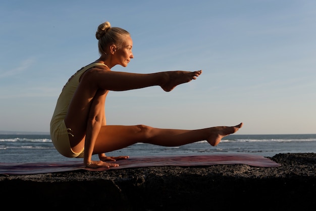 Bella donna che fa yoga sulla spiaggia