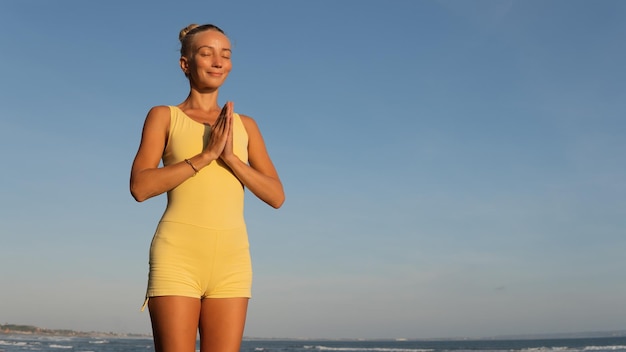 Bella donna che fa yoga sulla spiaggia