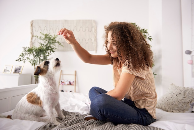 Bella donna che gioca con il cane sul letto