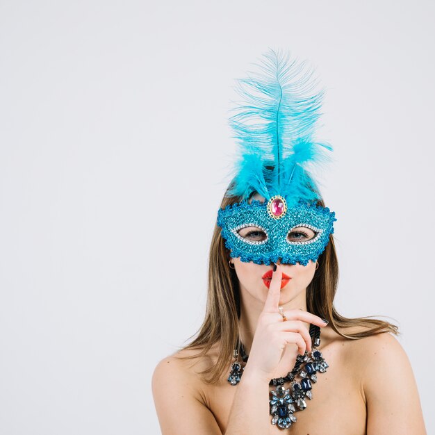 Bella donna che indossa la maschera di Carnevale con un dito sulle labbra