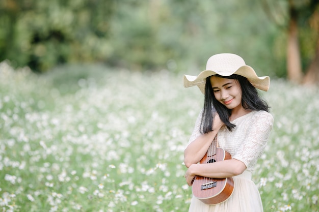 Bella donna che indossa un abito bianco carino e in possesso di un ukulele