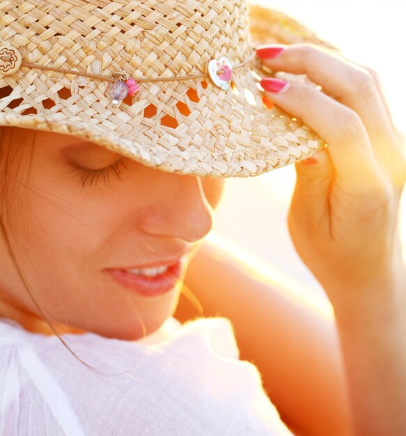 Bella donna che indossa un cappello nella luce del tramonto