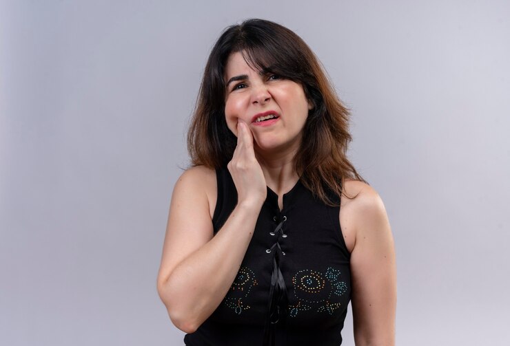 Foto gratuito bella donna che indossa una camicia nera che soffre di mal di denti tenendo la guancia con la mano