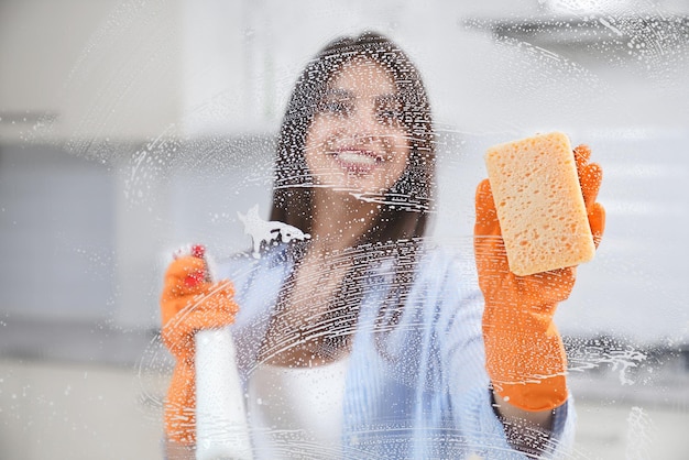 Bella donna che lava la finestra in guanti di gomma