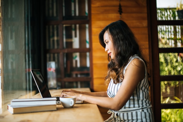 Bella donna che lavora con il computer portatile al caffè caffetteria