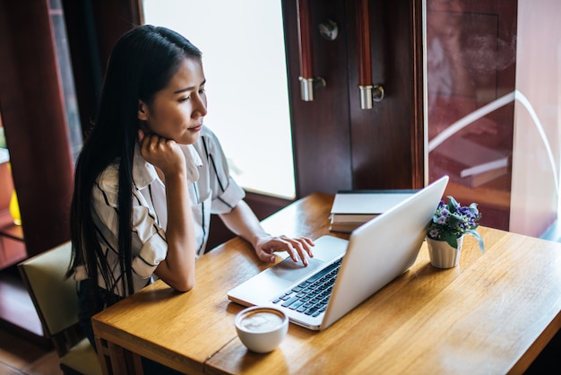 Bella donna che lavora con il computer portatile al caffè caffetteria