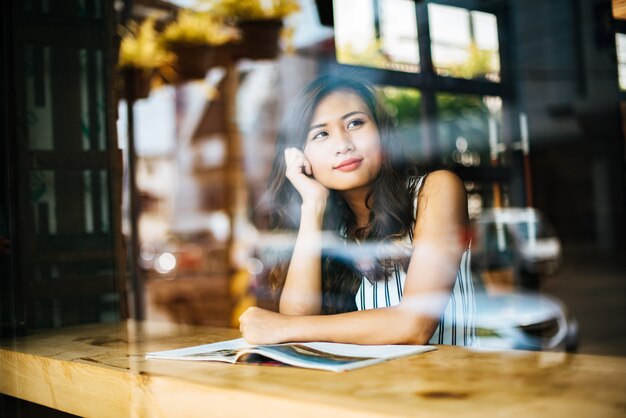 Bella donna che legge la rivista nella caffetteria