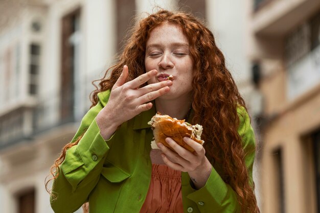 Bella donna che mangia delizioso cibo di strada all'aperto