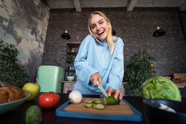 Bella donna che parla sul telefono cellulare in cucina a casa