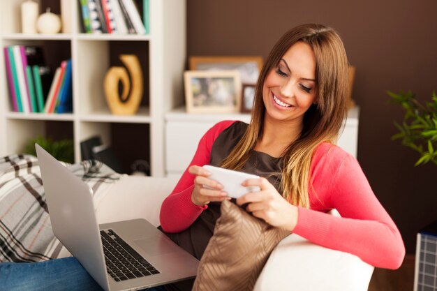 Bella donna che si distende con la tecnologia moderna a casa