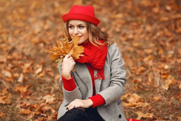 Bella donna che si siede in un parco di autunno