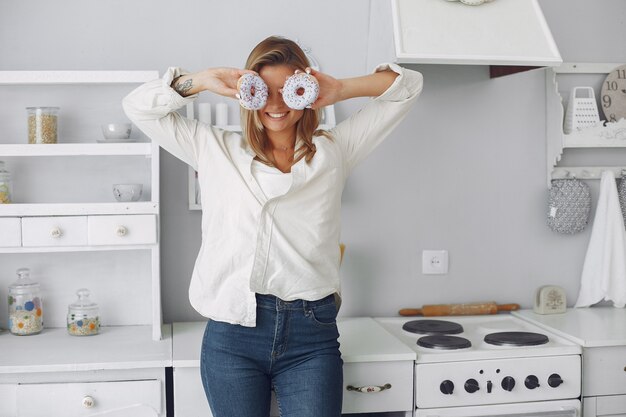 Bella donna che sta in una cucina con la ciambella