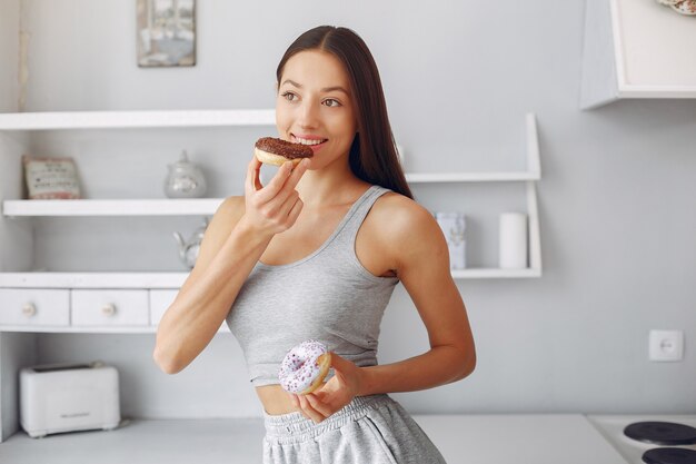 Bella donna che sta in una cucina con la ciambella