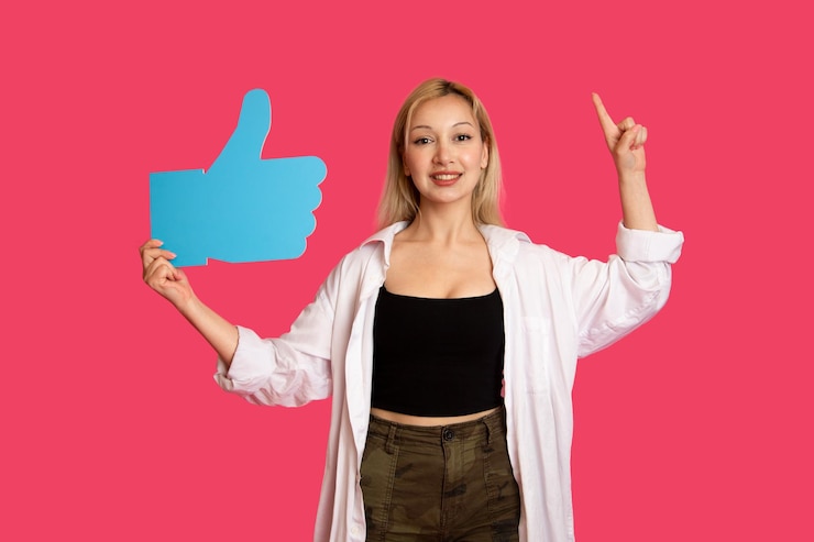Foto gratuito bella donna che tiene un pulsante mi piace isolato su sfondo rosa