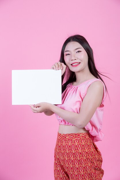 Bella donna che tiene uno strato del bordo bianco su una priorità bassa dentellare.