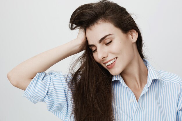 Bella donna che tocca i capelli con l'espressione soddisfatta e gli occhi chiusi