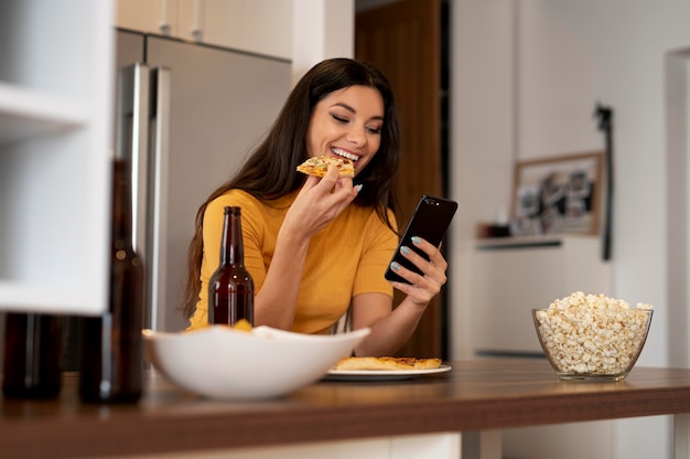 Bella donna che usa il telefono mentre mangia