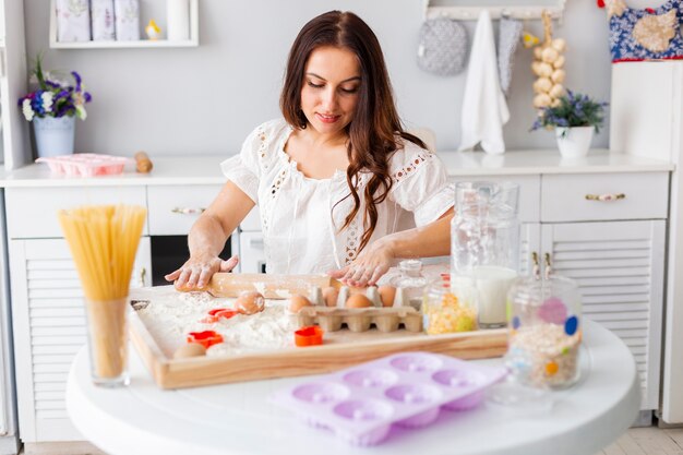 Bella donna che usando il rullo della cucina