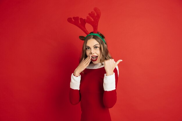 Bella donna come cervo di Natale isolato sul concetto di muro rosso