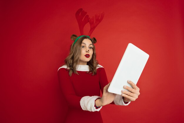 Bella donna come un cervo di Natale isolato sul muro rosso red