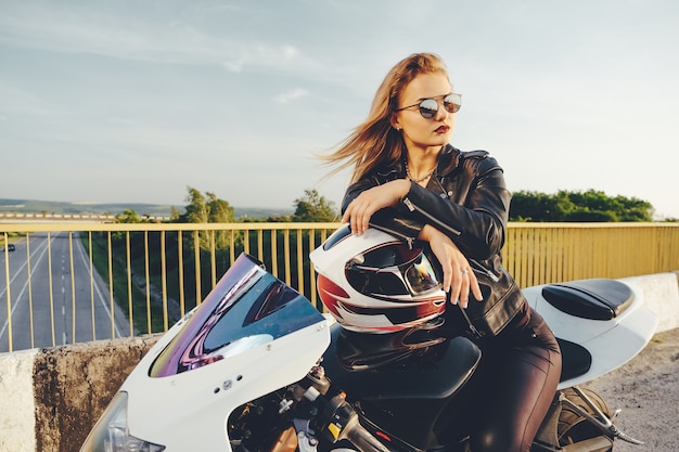 Bella donna con gli occhiali da sole guida su una moto