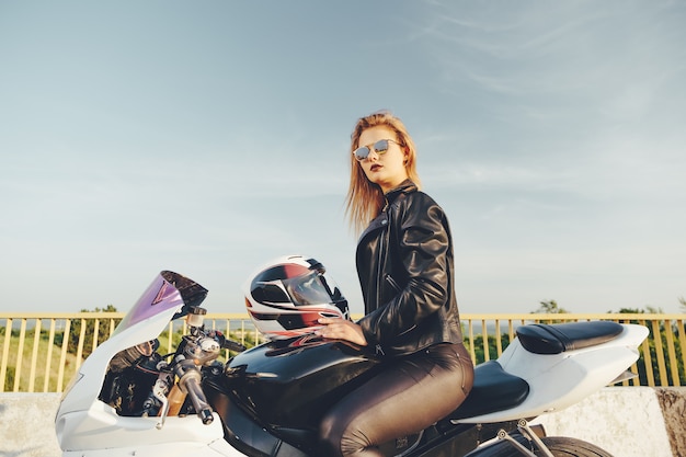 Bella donna con gli occhiali da sole guida su una moto