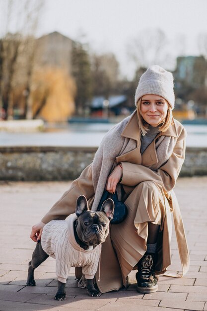 Bella donna con il bulldog francese che cammina nel parco