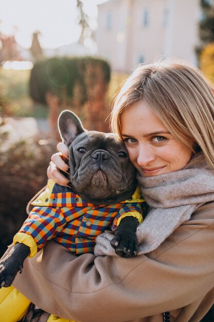 Bella donna con il bulldog francese che cammina nel parco