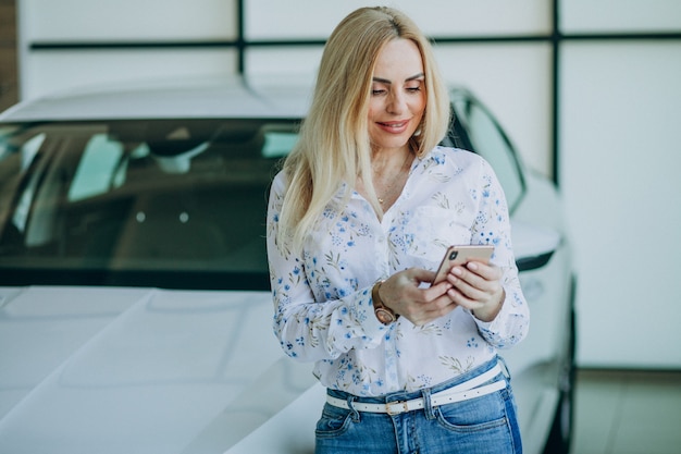 Bella donna con il telefono in autosalone