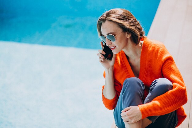 Bella donna con telefono seduto in piscina