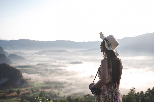 Bella donna con una macchina fotografica che sta sulla cima della montagna