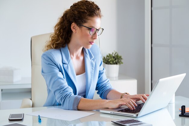 Bella donna d&#39;affari che lavora con il suo computer portatile in ufficio.