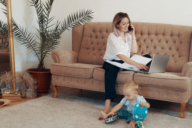 Bella donna d'affari, lavorando a casa. Concetto multi-tasking, freelance e maternità