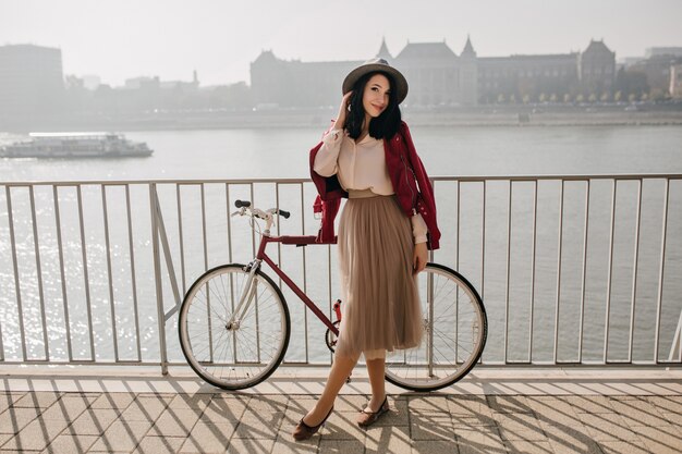 Bella donna dai capelli scuri in gonna trascorrere del tempo vicino al fiume