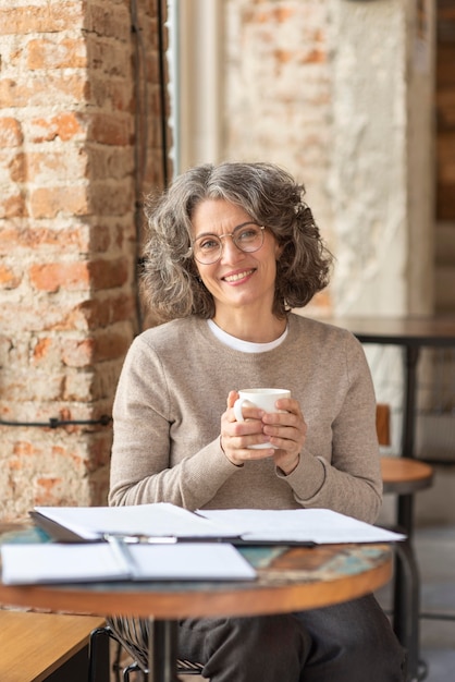 Bella donna del ritratto che gode della tazza di caffè mentre woking