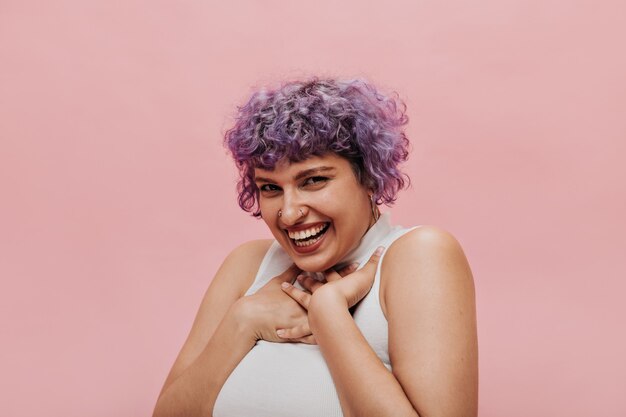 Bella donna deliziosa con i capelli lilla luminosi sembra carina. Sorridente donna dai capelli corti in posa.