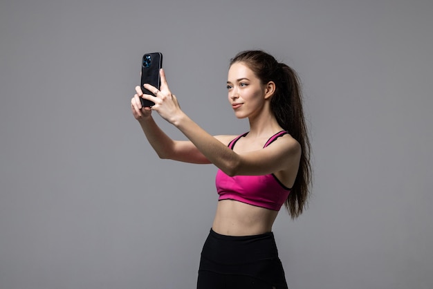 Bella donna di forma fisica che fa la foto del selfie su un bianco