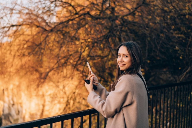 Bella donna elegante che sta in un parco in autunno