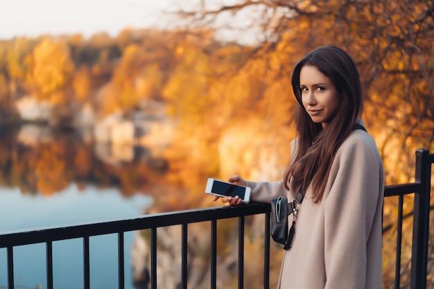 Bella donna elegante che sta in un parco in autunno