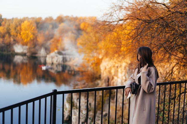 Bella donna elegante che sta in un parco in autunno