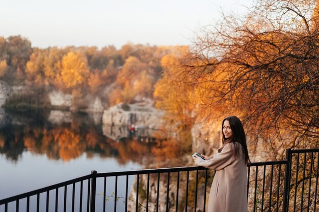 Bella donna elegante che sta in un parco in autunno