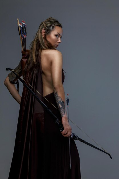 Bella donna elfo con arco e frecce. Isolato su grigio