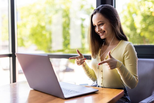 Bella donna freelance che parla in una videoconferenza on line e laptop in un desktop da ufficio o a casa