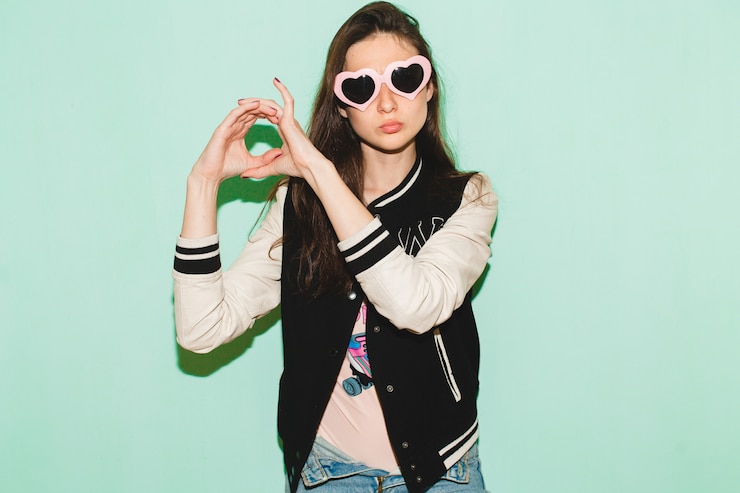Foto gratuito bella donna giovane hipster, occhiali da sole cuore divertente, contro il muro blu, espressione del viso fresco