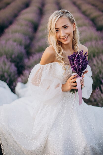 Bella donna in abito da sposa in campo di lavanda