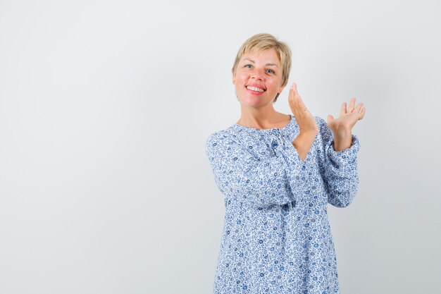 Bella donna in camicetta fantasia che applaude e che sembra allegra, vista frontale. spazio per il testo