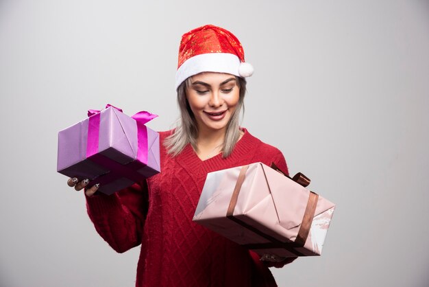 Bella donna in cappello della Santa che guarda felicemente i regali di Natale.