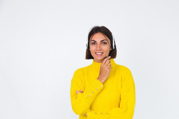 Bella donna in maglione giallo su bianco manager con cuffie felice sorriso accogliente positivo welcoming