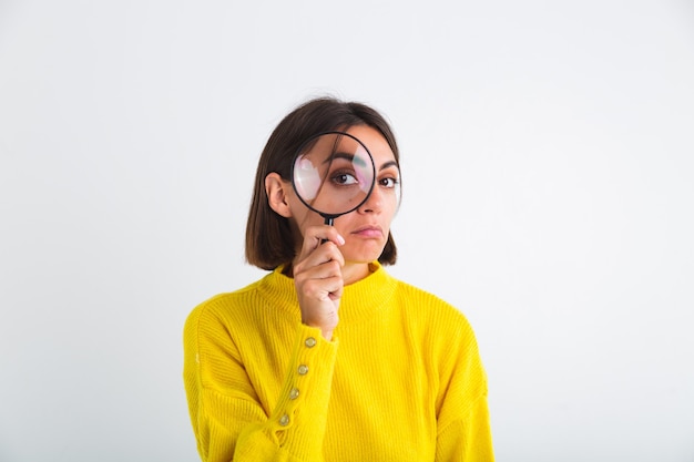 Bella donna in maglione giallo su lente d'ingrandimento tenuta bianca felice giocoso positivo